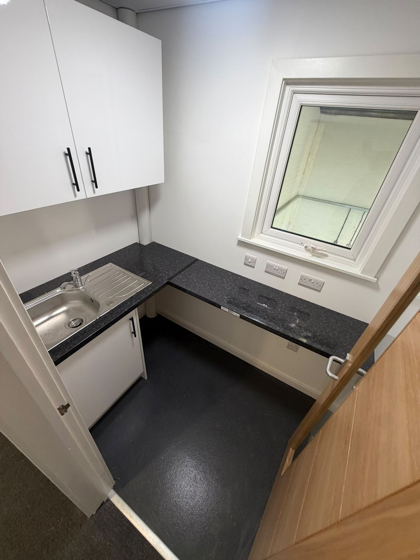 Compact kitchenette with wall units, mixer tap and power outlets