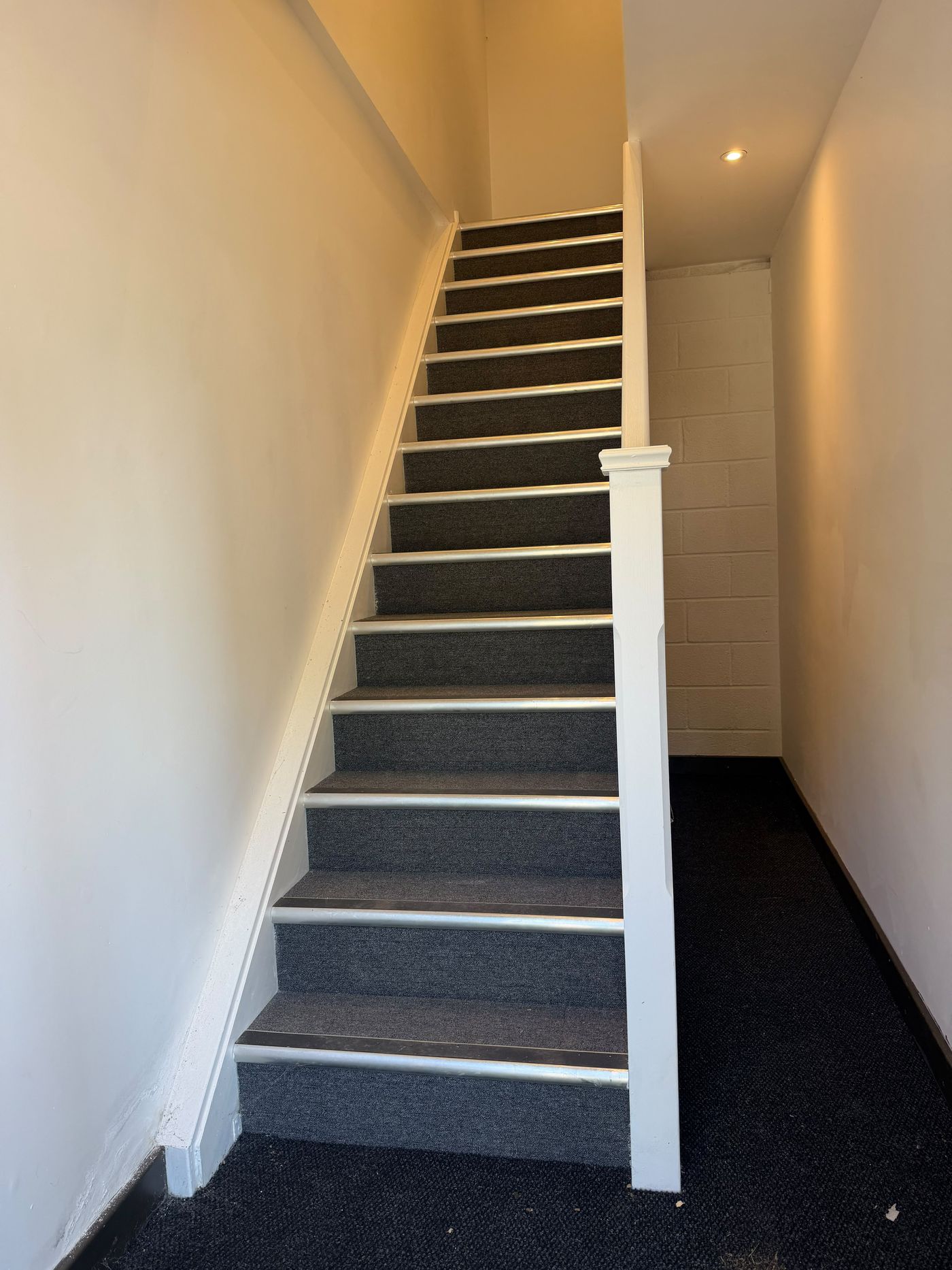 Carpeted staircase with aluminium safety nosings between ground and first floor