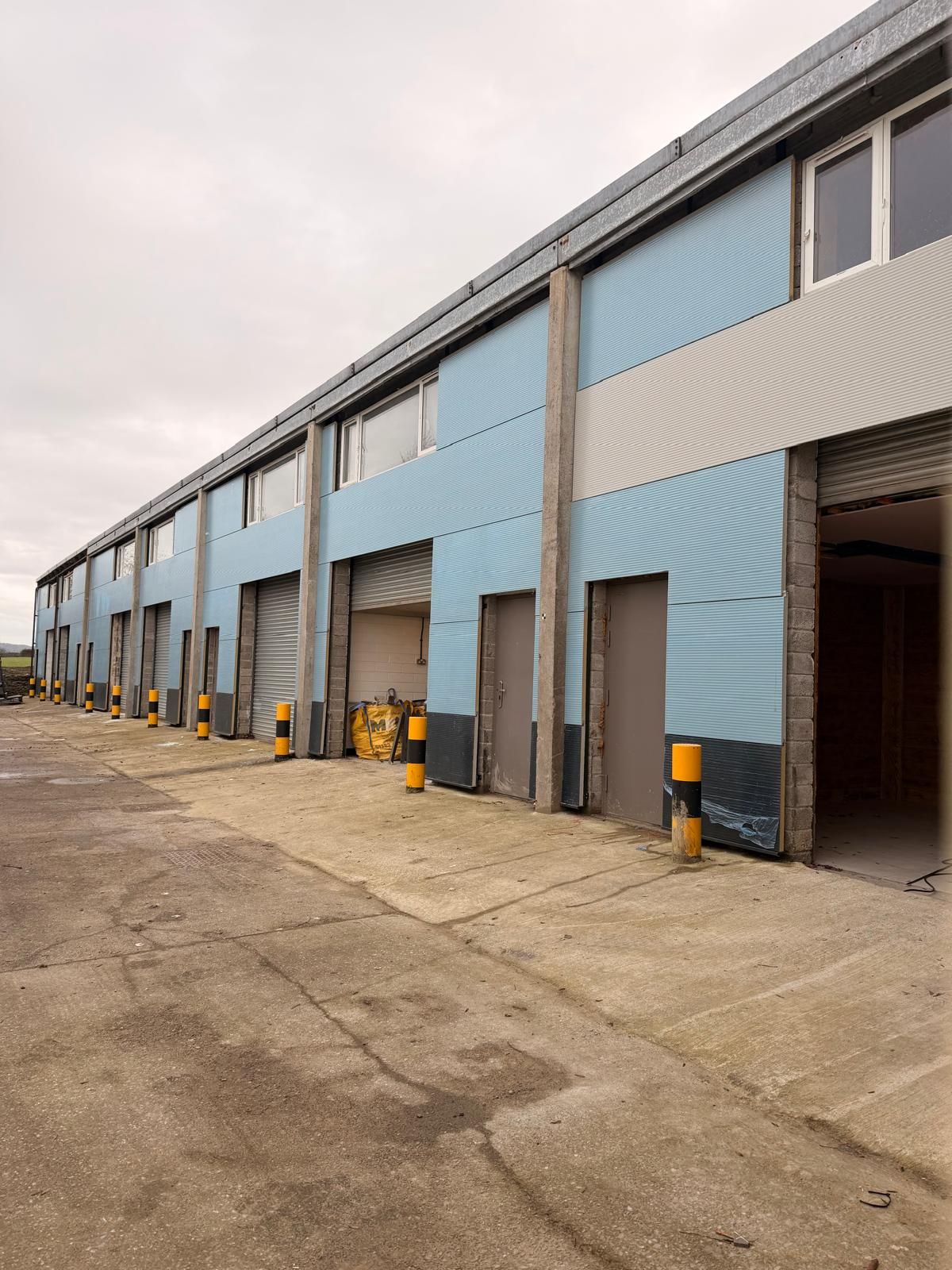 Exterior of West End Enterprise units with blue cladding, roller shutters and concrete yard